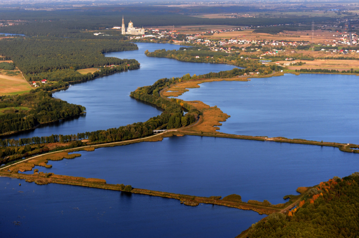 Fotografia z lotu ptaka przedstawiająca zbiorniki wodne i Jezioro Licheńskie z Bazyliką w tle