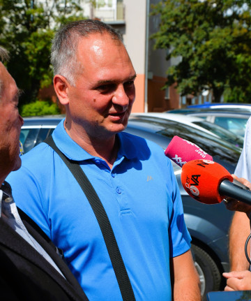 Mężczyzna w niebieskiej bluzce udziela wywiadu dziennikarzom.